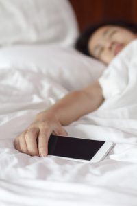 Woman sleeping in bed and holding a mobile phone.